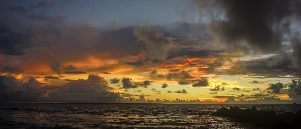Sunset on the beach with a dramatic sky with clouds and an orange hue Stock Photos