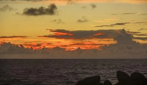 Sunset on the beach with a dramatic sky with clouds and an orange hue Stock Photos