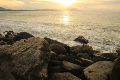 Sunset on the beach with lots of rocks Stock Photos