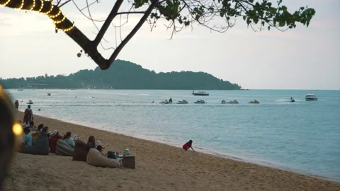 Sunset beach near a cafe. A tree on the beach wrapped in neon ribbon. Stock Footage 237745708
