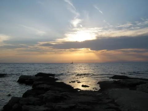 Sunset on the beach over the ocean behind clouds Stock Photos