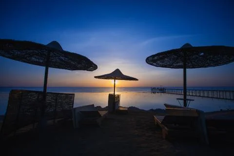 Sunset on the beach with parasol Stock Photos