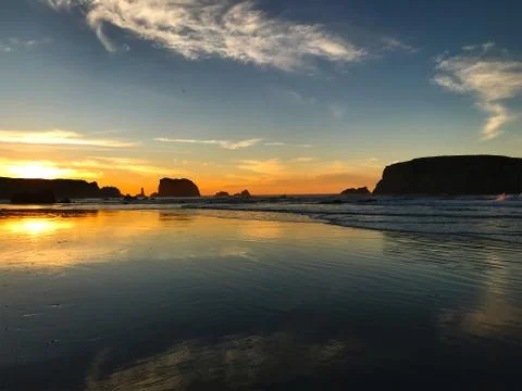Sunset beach, reflections, and clouds Stock Photos