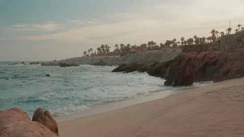 Sunset on the beach with rocks in the background and some palm trees. Video stock 280446766