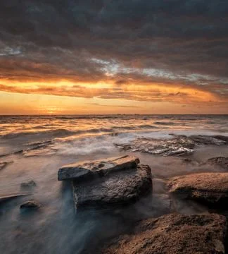 Sunset at the beach with rocks Stock Photos