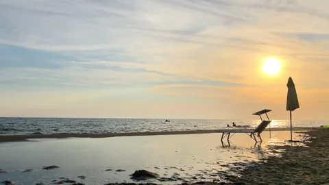 Sunset Beach Scene with Empty Chair and Umbrella by the Calm Sea Stock Footage 341380597