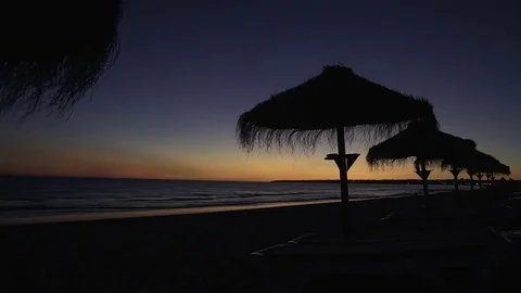 Sunset on the beach with silhouettes of the straw umbrellas against the sky. Stock Footage 83323069