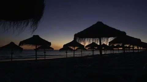 Sunset on the beach with silhouettes of the straw umbrellas against the sky. Stock Footage 84234016