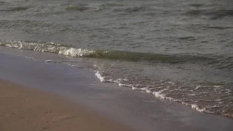 Sunset on the beach - the slow movement of foamy waves rolling towards the beach Video stock 254890722
