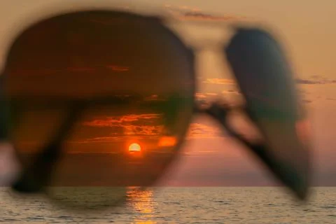 Sunset on beach in summer evening through sunglasses Stock Photos