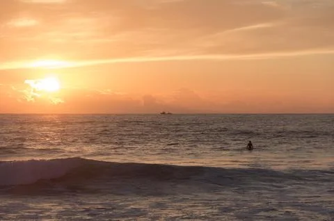 Sunset beach with a surfer on the board Stock Photos