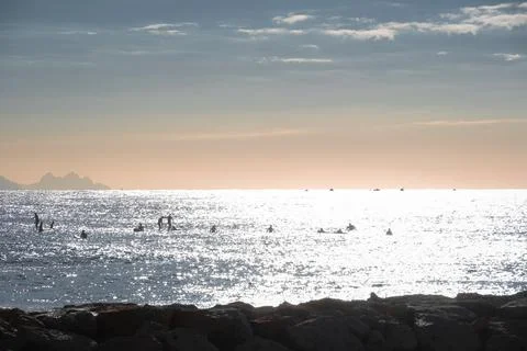 Sunset on the beach with surfers in water Stock Photos