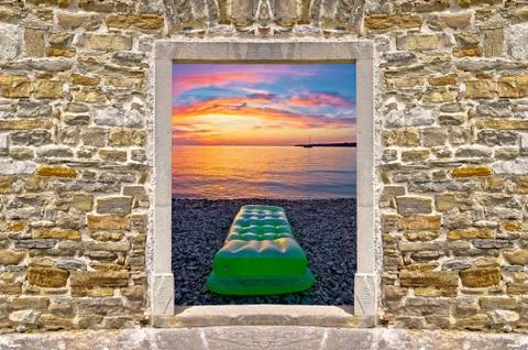 Sunset on beach through stone wall door Stock Photos
