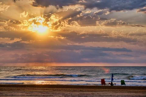 Sunset at the beach with two chairs, ocean waves, and clouds in the sky ove.. Foto stock
