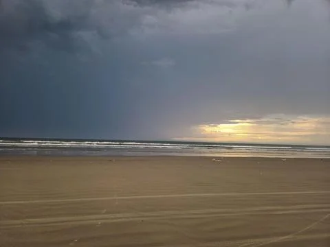 Sunset on the beach under a dark sky Stock Photos