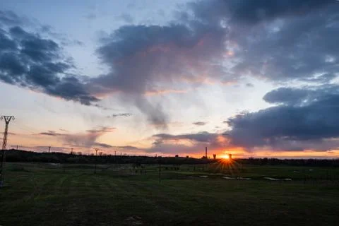 Sunset with a beautiful sky on a golf course and a coal mine in the backgroun Stock Photos
