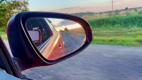 The sunset is beautifully reflected in the mirror of a moving car. Stock-Footage 252561690