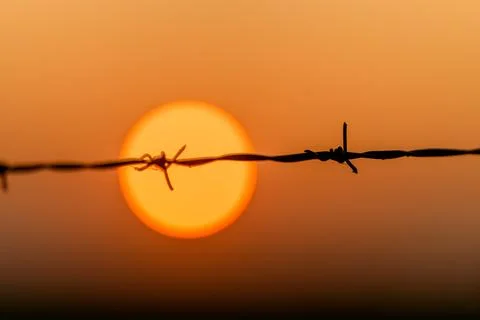 The Sunset Behind Barbed Wire A Powerful Symbol Representing Division and Resili Stock Photos