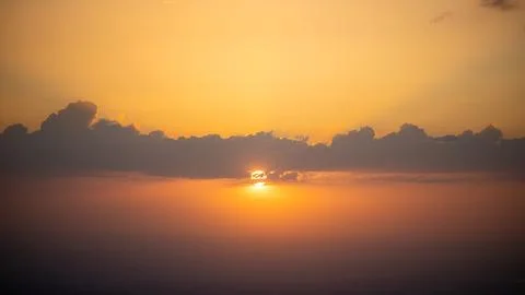Sunset Behind the Clouds Over the Horizon Stock Photos