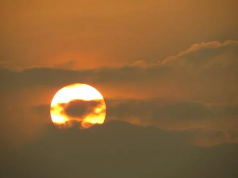 Sunset behind clouds Stock Photos