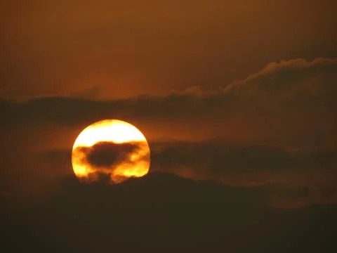 Sunset behind clouds Stock Photos