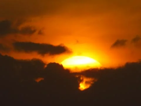 Sunset behind clouds Stock Photos