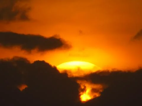 Sunset behind clouds Stock Photos