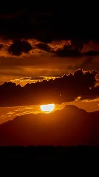 Sunset behind dark clouds, creating a dramatic and moody evening sky scene. Stock Photos