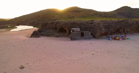 A sunset behind the hills of the beach scenery while drone pans up Stock-Footage 97768080