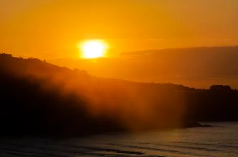 Sunset behind a mountain by the ocean Stock Photos