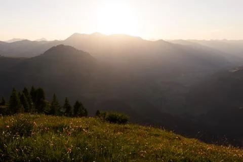 Sunset behind mountain range and green meadows in alpine region Foto stock