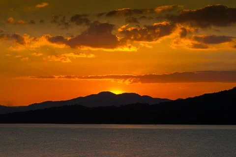 Sunset behind mountain reflection on water in dam Stock Photos