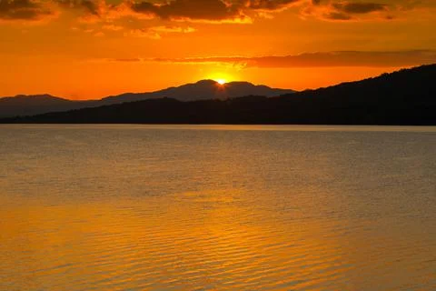 Sunset behind mountain reflection on water in dam Stock Photos