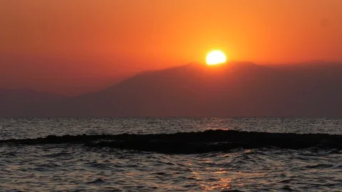 Sunset behind a mountain with slow motion waves Stock Footage 119227665