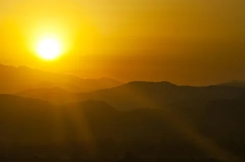 Sunset behind mountains Stock Photos