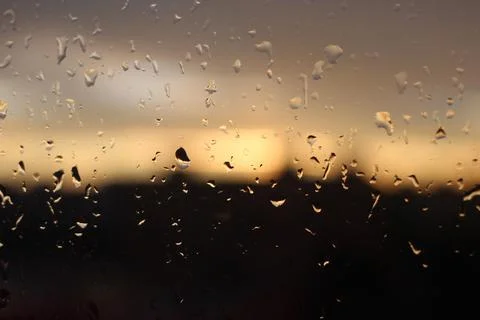 Sunset behind raindrops flowing down the window Stock Photos