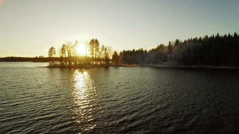 Sunset behind small island at unfrozen lake. Aerial shot. Stock Footage 86153115