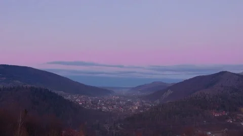 Sunset between mountains over the city. Beautiful time lapse from day to nighte Stock Footage 83819707