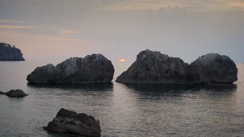 Sunset between two silhouetted rocks in calm Mediterranean sea Stock Footage 160987682