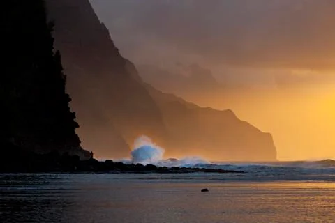 Sunset with a big wave explosion at the Na Pali Coast in Kauai, Hawaii. Stock Photos