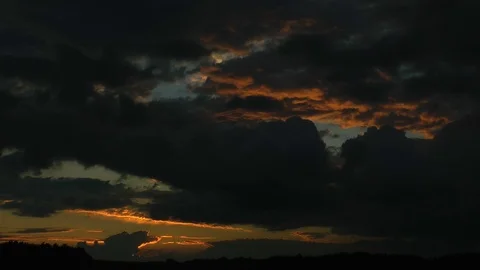 Sunset. Black clouds are painted in red color setting the sun. Time-lapse. Stockbeeldmateriaal 69977104