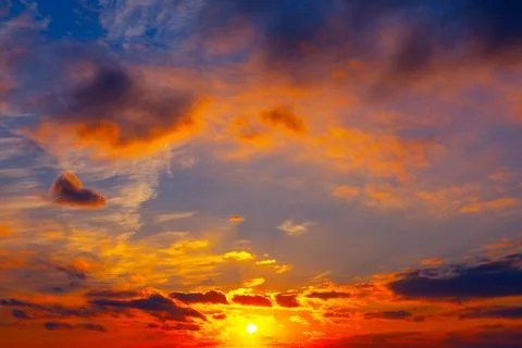 Sunset blazes across sky with sun glowing near horizon Stock Photos