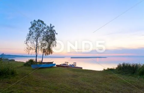 Sunset with boats near the summer lake shore Stock Photos