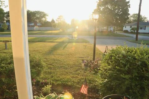 Sunset  bokeh behind light post with small American flag 库存照片