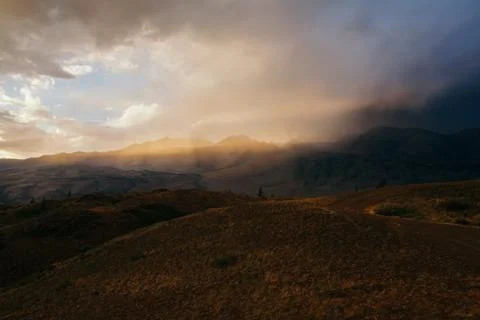 Sunset, bright sunlight in a dusty cloud, travel on the mountain valley, a Stockfoto's