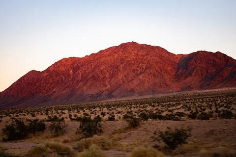 Sunset brings out the deep red of the nearby desert hills Stock Photos