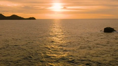 Sunset casting golden light over ocean waves and rock formations. Seychelles Stock Footage 307002499
