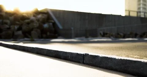 Sunset casting shadows on a deserted urban pathway near rocks Stock Illustration