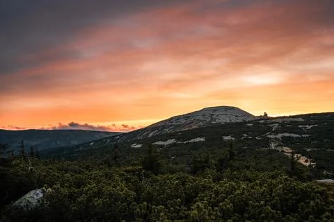 A sunset casting vibrant colors over mountains and lush trees Stock Photos