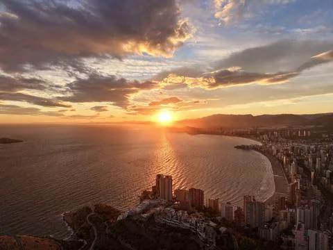 Sunset casts striking shadows over serene bay with reflective orange light and Stock Photos
